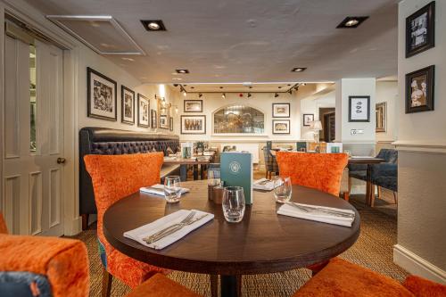 a dining room with a wooden table and orange chairs at The Crown Hotel, Boroughbridge, North Yorkshire - The Coaching Inn Group in Boroughbridge