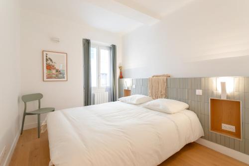 ein Schlafzimmer mit einem großen weißen Bett und einem Stuhl in der Unterkunft T3 ** BALCON ** VIEUX PORT ** CENTRE in Marseille