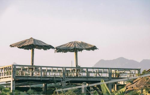 two umbrellas on a boardwalk with tables and chairs at Tiệm Cà Phê Mer Homestay & Coffee Mộc Châu in Mộc Châu