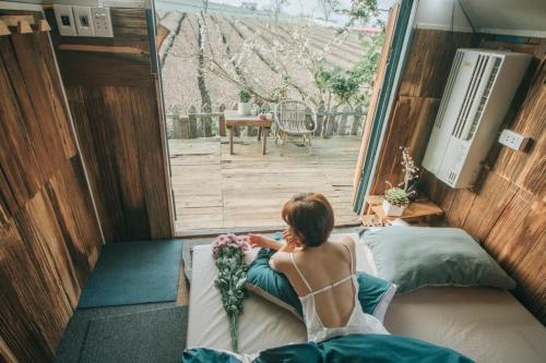 a woman sitting on a bed in a room with a window at Tiệm Cà Phê Mer Homestay & Coffee Mộc Châu in Mộc Châu