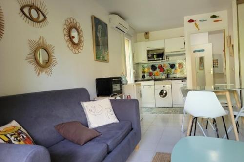 Il comprend un salon avec un canapé bleu et une cuisine. dans l'établissement Nice studio 30 m with terrace and pool, à Antibes