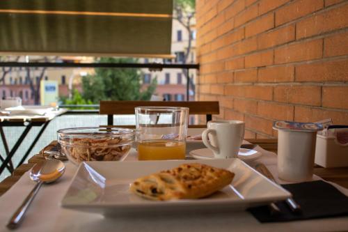un tavolo con un piatto di cibo e un bicchiere di succo d'arancia di B&B JONIO Roma a Roma
