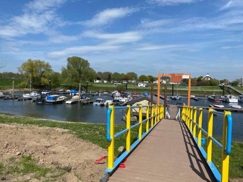a wooden dock with a yellow railing next to a marina at LUXUS Cube Ferienhaus Chalet am See mit Schwimmbad in Lathum NL in Lathum