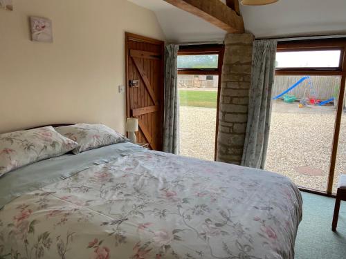 a bedroom with a bed and a large window at Stable Cottage, Old Mill Farm, Cotswold Water Park in Cirencester
