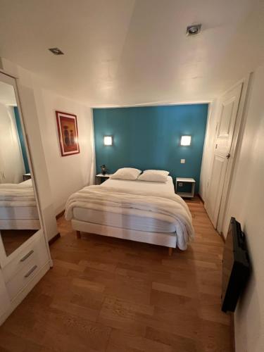 - une chambre avec un grand lit et un mur bleu dans l'établissement Le salinois, à Salins-les-Bains