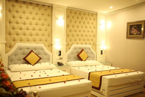 two beds in a hotel room with red specks on them at Kawasaki Hotel Cầu Giấy in Hanoi