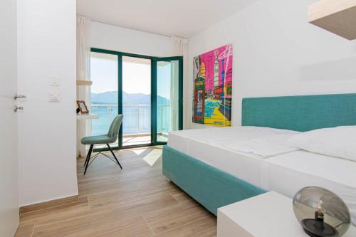 a white bedroom with a bed and a chair at Bliss on the Bay in Njivice