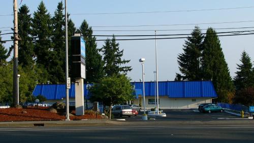 a building with a blue roof and cars parked in a parking lot at Oyster Bay Inn & Suites in Bremerton