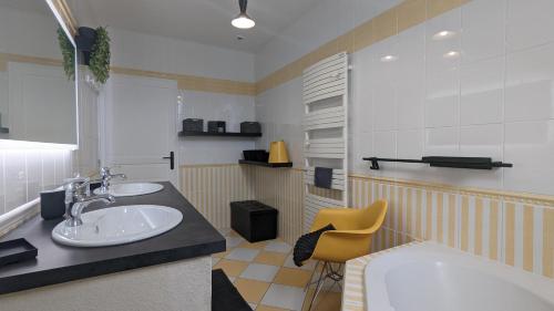 ein Badezimmer mit zwei Waschbecken und einem gelben Stuhl in der Unterkunft Le Moulin de la Motte in Bellenot-sous-Pouilly