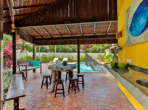 a patio with a table and chairs and a pool at A Casa de Porto in Porto De Galinhas