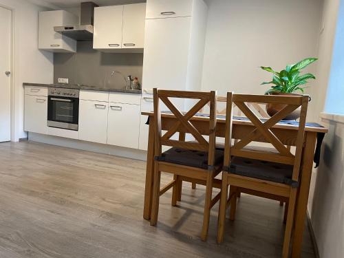 uma cozinha com uma mesa e 2 cadeiras e uma cozinha com armários brancos em Ferienwohnung Kaffeeduft em Reutte