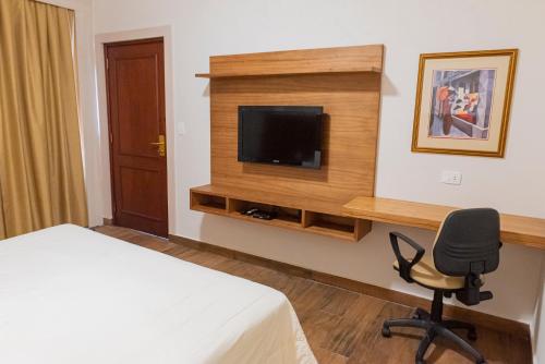 a hotel room with a bed and a chair and a television at Sabe Center in Asuncion