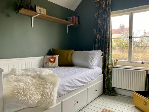 een slaapkamer met een wit bed en een raam bij Historic Family Cottage - Central Frome in Frome