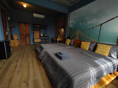 a large bed in a room with a painting on the wall at โรงแรม บอร์ดดิ้งเฮ้าส์ in Ban Bang Yai Chuai