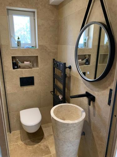 a bathroom with a toilet and a round mirror at Belle suite parentale in Laize-la-Ville