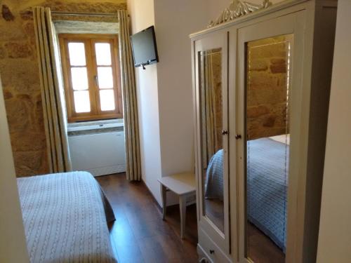 a bedroom with a bed and a dresser with a mirror at A Cantaruxa Maruxa Turismo Rural in Mondariz