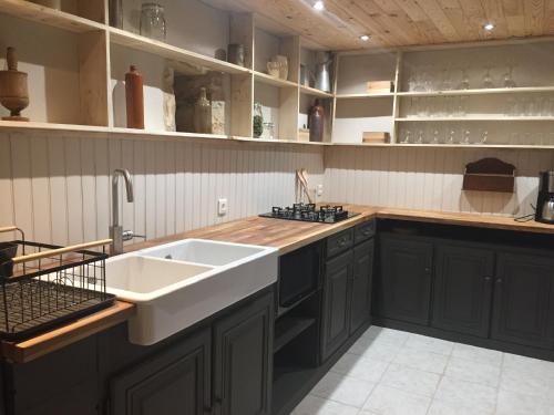a kitchen with black cabinets and a white sink at Gîte Dordogne Périgord in Hautefort