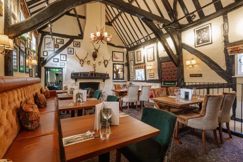 een restaurant met houten tafels en stoelen en een open haard bij The George Hotel, Dorchester-on-Thames, Oxfordshire in Dorchester on thames