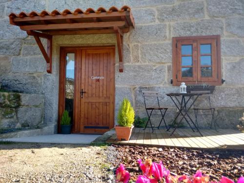 a stone house with a wooden door and a table at A Cantaruxa Maruxa Turismo Rural in Mondariz