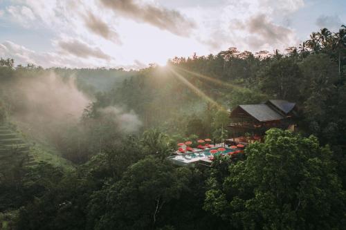 an aerial view of a resort in the forest with the sun shining at Buahan, a Banyan Tree Escape in Payangan