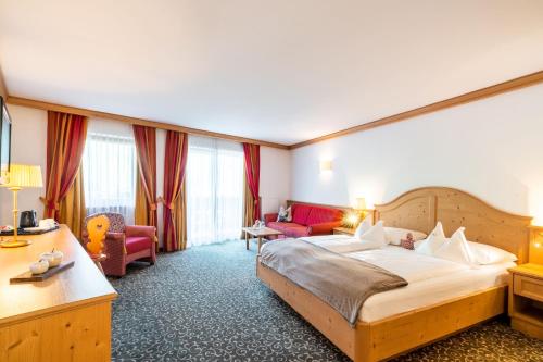 a hotel room with a large bed and a couch at Hotel Sun Valley in Selva di Val Gardena