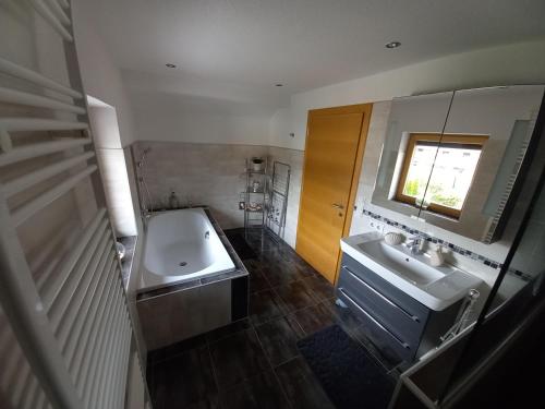 a bathroom with a tub and a sink and a mirror at Ferienwohnung Bergtroll in Uderns