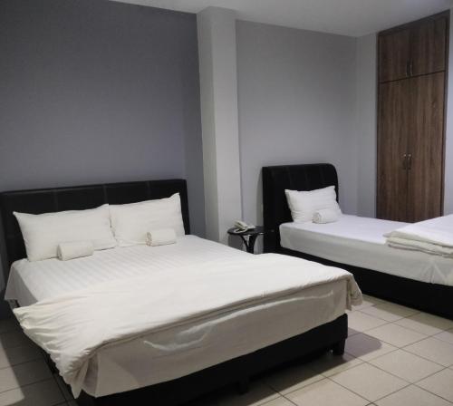 1 dormitorio con 2 camas y almohadas blancas en Reintree Lodge Hotel, en Ipoh