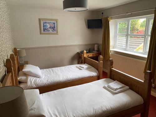 a room with two beds and a window at The Bullshead, Arthingworth House B&B in Market Harborough