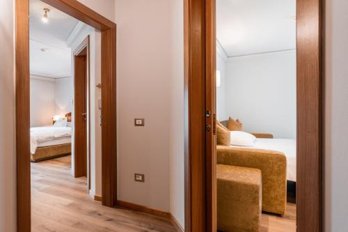 a room with two beds and a door to a bedroom at Hotel Sun Valley in Selva di Val Gardena