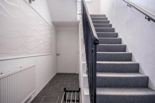 a staircase in a house with grey stairs and a door at The Douglas - Spacious 2 bed apartment in Uddingston in Uddingston