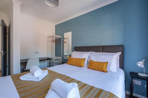 a bedroom with a large white bed with orange pillows at The Douglas - Spacious 2 bed apartment in Uddingston in Uddingston