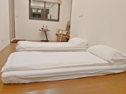 two white beds sitting on the floor in a room at 榛品包棟民宿 in Puli