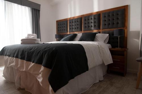 a bedroom with a large bed with a wooden headboard at Rozas Apart in Ezeiza