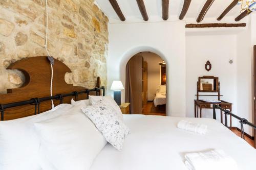 a bedroom with a large white bed with a stone wall at Cortijo mirasol in Santa Cruz de Comercio