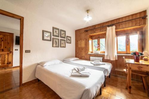 a bedroom with two beds and a window and a table at Hotel & Restaurant Perret - Mountain People in Valgrisenche