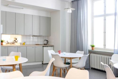 a kitchen and dining room with white tables and chairs at Hostel Bjorkenheim in Seinäjoki