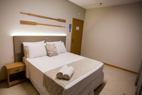 1 dormitorio con 1 cama blanca grande y toallas. en Mar de Canasvieiras Hotel e Eventos, en Florianópolis