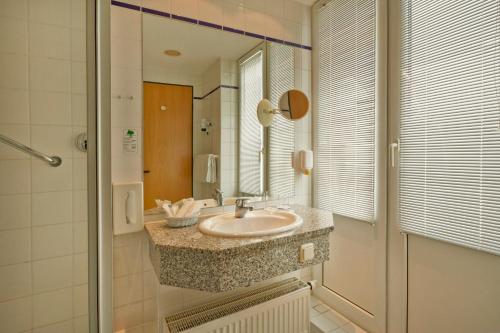 a bathroom with a sink and a mirror at H+ Hotel & SPA Friedrichroda in Friedrichroda