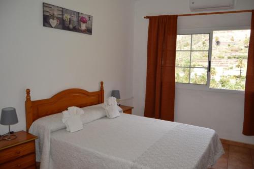 a bedroom with a bed with white sheets and a window at Casa Rural Guadá in Valle Gran Rey