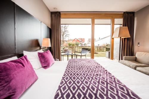 a bedroom with a large bed with purple pillows at Hotel Restaurant Spa Torkel in Nonnenhorn