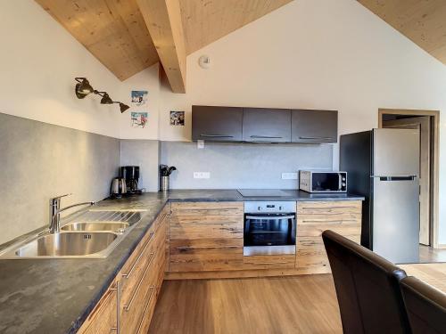 une cuisine avec des armoires en bois et des appareils en acier inoxydable dans l'établissement Appartement spacieux 10 pers, 80 m², avec balcon sud, au pied des pistes à Fontcouverte-la-Toussuire - FR-1-417-38, à La Toussuire