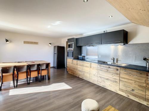 une grande cuisine avec des placards en bois et une table dans l'établissement Appartement spacieux 2 étoiles, proche télésiège, 60m² pour 6 personnes, ensoleillé, parking inclus - FR-1-417-47, à La Toussuire