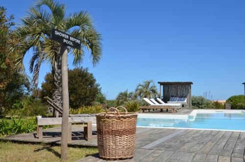 a sign next to a palm tree next to a swimming pool at Casa Suaya in José Ignacio