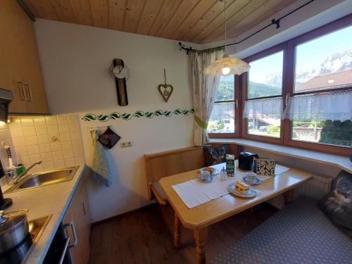een keuken met een tafel, een wastafel en een raam bij Haus am Forstamt 11 Ferienwohnungen in Ramsau