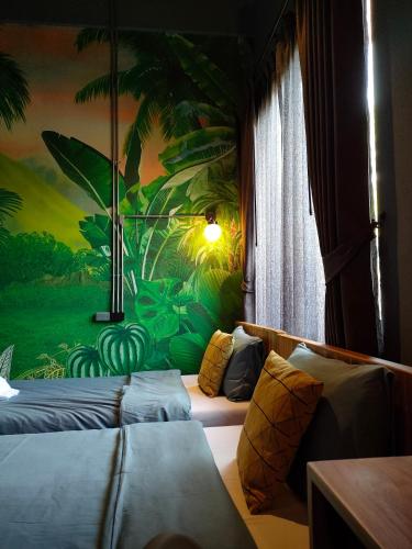 a room with two beds and a painting on the wall at โรงแรม บอร์ดดิ้งเฮ้าส์ in Ban Bang Yai Chuai
