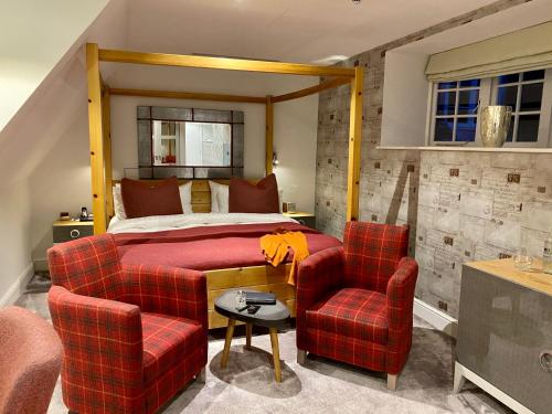 a bedroom with a bed and two chairs at Barnett Hill Hotel in Guildford