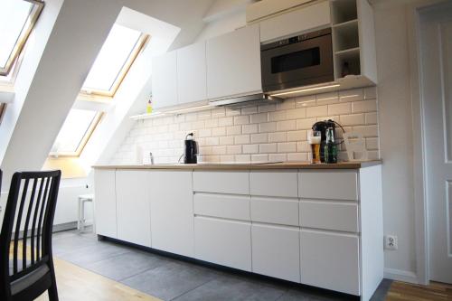 a kitchen with white cabinets and a microwave at Serce miasta -Mostowa Bydgoszcz in Bydgoszcz