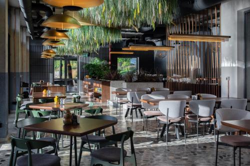 een restaurant met tafels, stoelen en planten bij ARCA Resort 