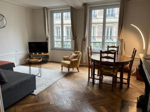 sala de estar con mesa, sillas y TV en APPARTEMENT COSY CENTRE HISTORIQUE, en Caen