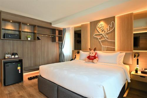 a teddy bear sitting on a bed in a hotel room at Moose Hotel Nimman in Chiang Mai